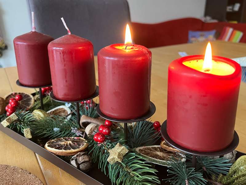 12 von 12 Dezember 2024 - 11 von 12 - Adventsgesteck mit 4 roten Kerzen. 2 mit Flammen