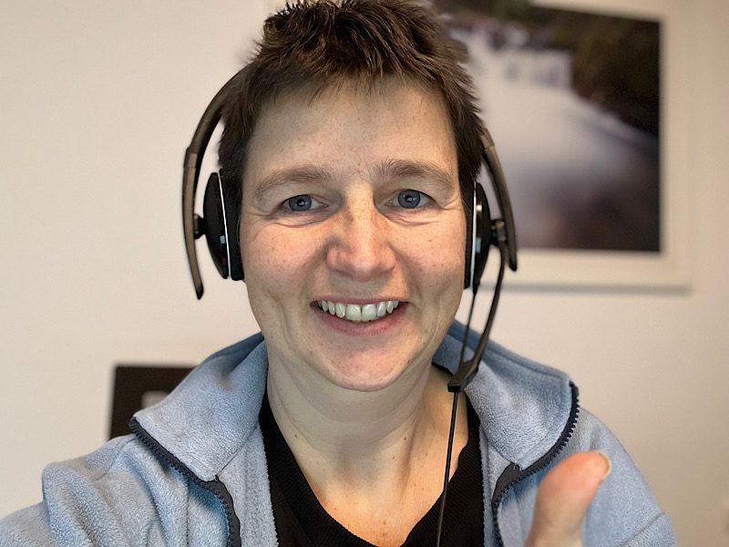 Danielle Berg mit Headset vor dem Bildschirm, lächelnd