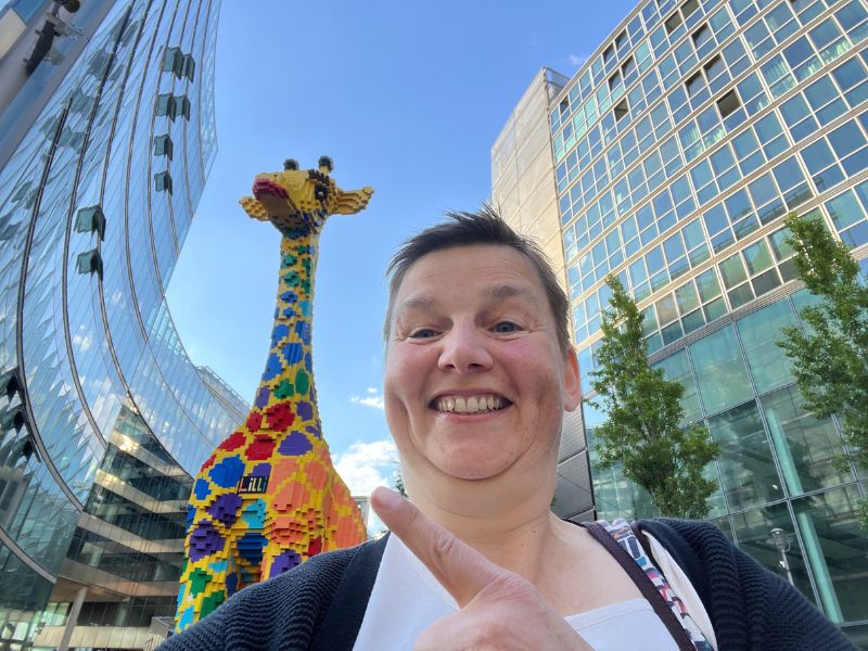 12 von 12 Mai 2025 - 9 von 12 - Auf geht's zum Netzwerktreffen - Danielle Berg vor Giraffe am Lego Discovery Center Berlin