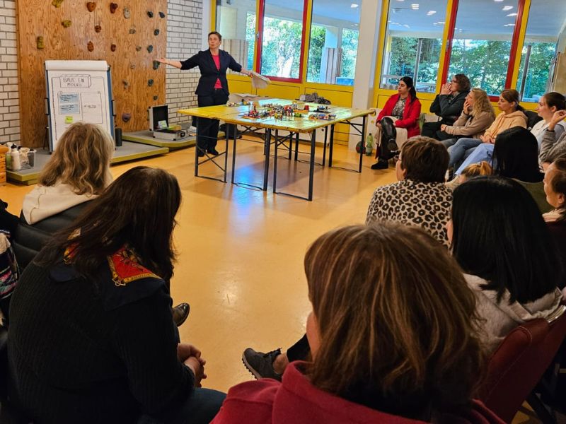 LSP Workshop Kita Setting - Danielle Berg moderiert an Tischen mit Lego-Modellen und Workshop Teilnehmende hören aufmerksam zu