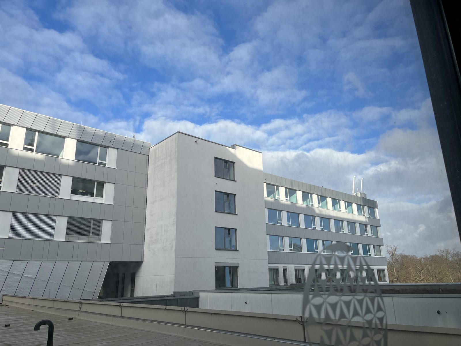 Blick aus dem Klinikfenster auf die gegenüberliegenden Gebäude unter blauem Himmel
