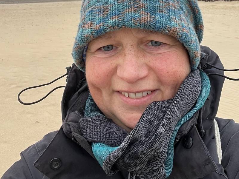 Danielle Berg mit Jacke und Mütze am Strand